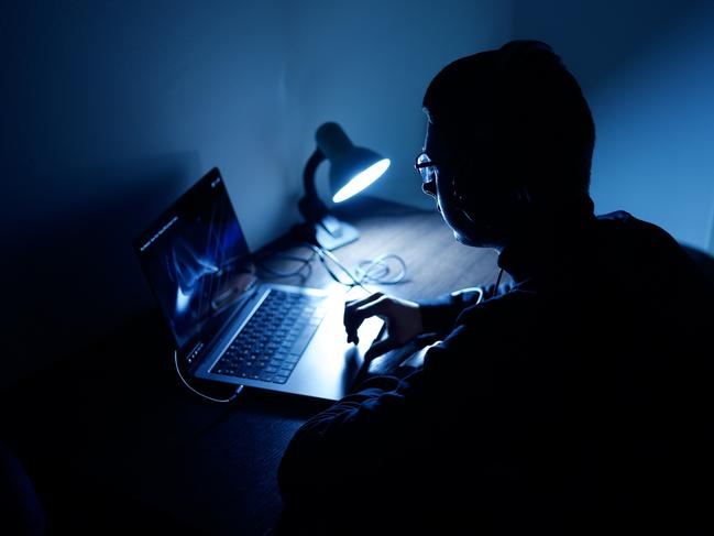 Young freelancer in his room, working at home on laptop in dark atmosphere