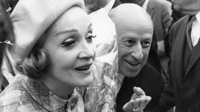 Marlene Dietrich in Adelaide for performances in the 1968 Adelaide Festival of Arts. Pictured on arrival at Adelaide, smiling as she accepts a sheaf of flowers, with her is entrepreneur Kenn Brodziak on March, 5 1968.