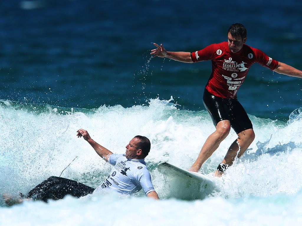 Tony Abbott wipes out in front Mike Baird during the 2010 Manly Festival of Surfing at Manly Beach in Sydney.