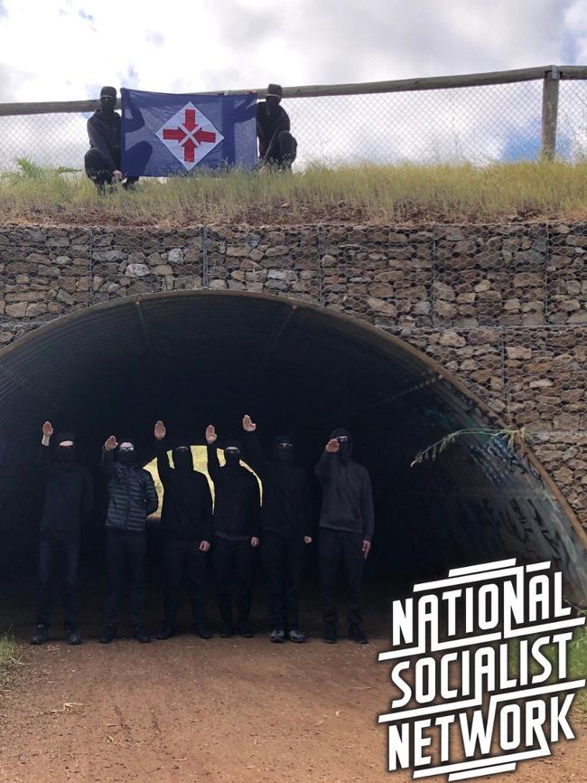 The Adelaide branch of the neo-nazi group, the National Socialist Network, gather to perform the Hitler salute under a bridge in the darkness, hiding their identities.