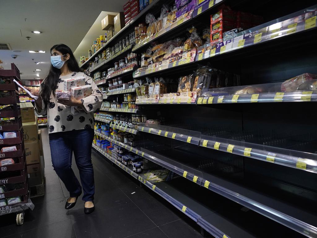 A woman walks past an empty shelf for breads at a supermarket in Hong Kong, Saturday, Feb. 15, 2020. China reported Saturday a figure of 2,641 new virus cases, a major drop from the higher numbers in recent days since a broader diagnostic method was implemented. (AP Photo/Vincent Yu)