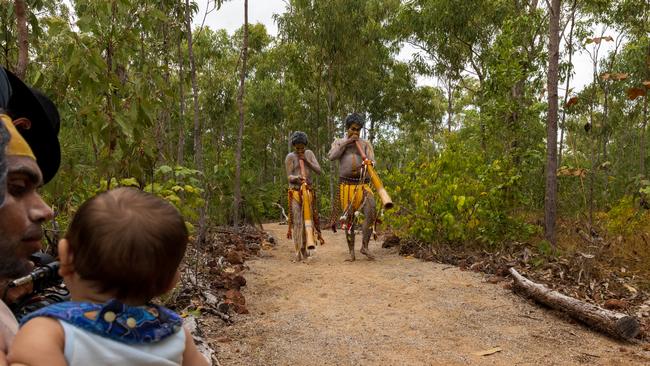 Yolngu boys playing didgeridoo (Yidaki) as a man with his baby looks on during the Garma Festival 2022. Picture: Tamati Smith/Getty Images