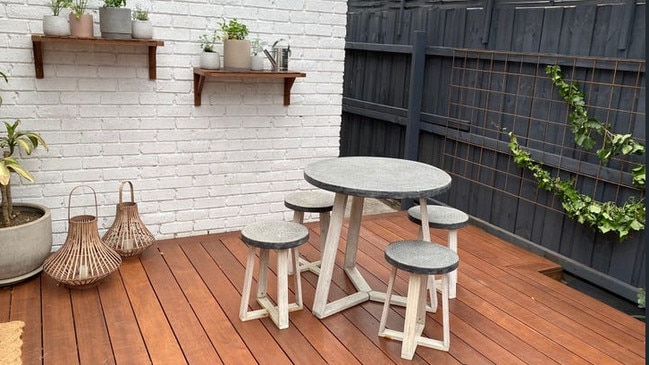 Glass sliding doors lead to the undercover deck and turf garden courtyard with built-in bench seating and high fencing.