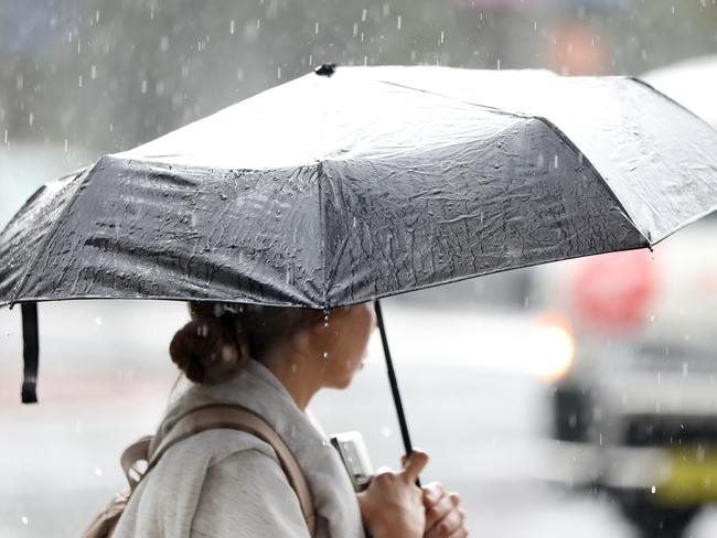 SYDNEY, AUSTRALIA - NewsWire Photos FEBRUARY 25: A woman pictured in the rain holding an umbrella on the corner of Liverpool and Elizabeth street in the Sydney CBD.Picture: NCA NewsWire / Damian Shaw