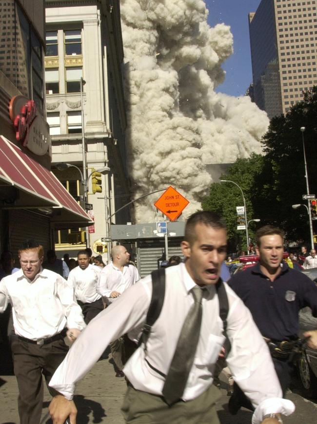 People run as rubble from a collapsed tower shoots down a nearby street. Picture: AP