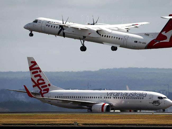 A Virgin Airways plane travels down the runway as a QantasLink Dash 8-400 series plane takes off at Sydney's Kingsford Smith international airport on November 3, 2023. (Photo by DAVID GRAY / AFP)