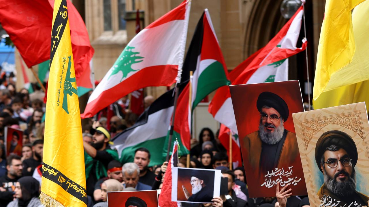 People hold up the Hezbollah flag and the Hezbollah leader Hassan Nasrallah at a protest at Town Hall in Sydney Picture: NewsWire / Damian Shaw