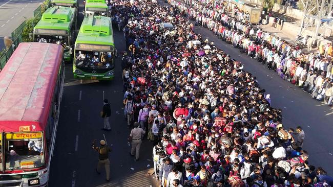 Migrant workers and their family members line-up outsdie the Anand Vihar bus terminal to leave for their villages on Saturday. Picture: Bhuvan Bagga/AFP