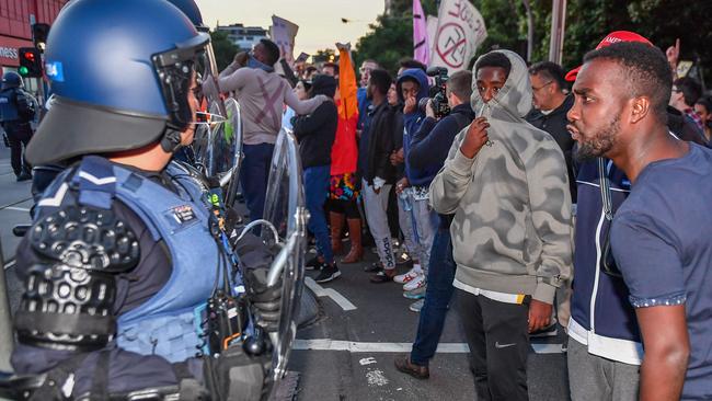 Angry locals from the adjacent blocks taunt police. Picture: Jake Nowakowski