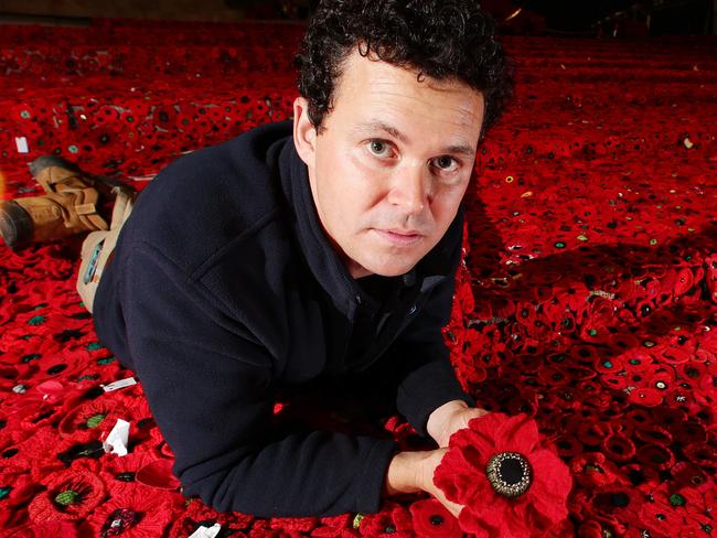 200,000 crochet poppies being installed in Fed Square for Anzac Day. Landscape Designer Phillip Johnson with some of the 200,000 crocheted poppies at Federation Square Picture: Norm Oorloff