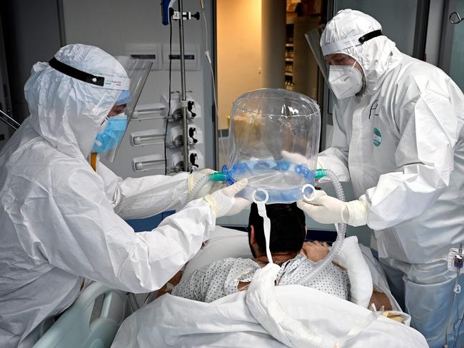 In this file photograph taken on December 30, 2021, medical staff members help a patient to wear a new non-invasive technology that can reduce the need of intubation at Covid-19 intensive care unit (ICU) at The Institute of Clinical Cardiology (ICC) in Rome. - The Covid-19 pandemic, which for over three years has killed millions of people, wreaked economic havoc and deepened inequalities, no longer constitutes a global health emergency, the WHO said on May 5, 2023. It is "with great hope that I declare Covid-19 over as a global health emergency", WHO chief Tedros Adhanom Ghebreyesus told reporters, estimating that the pandemic had killed "at least 20 million" people, nearly three times the official estimate. (Photo by Alberto PIZZOLI / AFP)