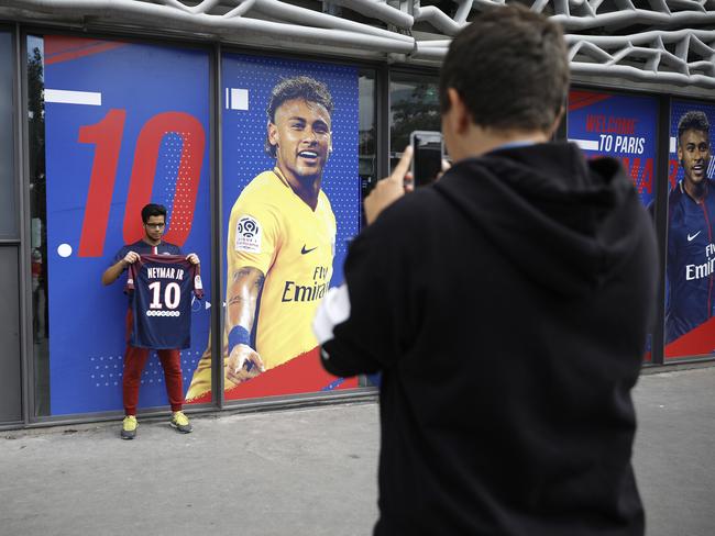 A man waiting for the arrival of Neymar poses with a PSG shirt.