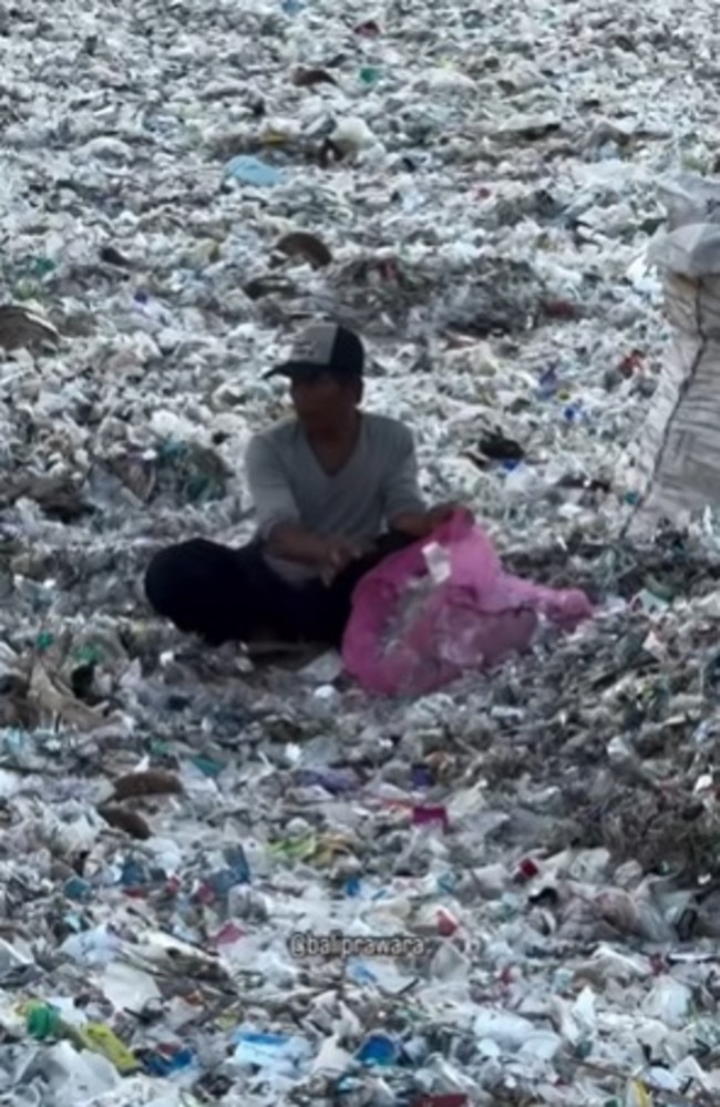 A local sitting among piles of rubbish, picking up the waste one by one. Picture: Instagram/canggubalinews