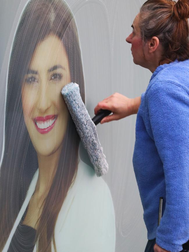 Daily Telegraph July 28/7/22. A cleaner tries to clean an image of member for Miranda Eleni Petinos mp on her electoral office window .picture John Grainger