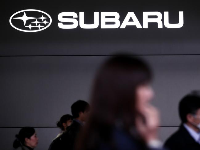 People walk past the logo of Japan's automaker Subaru outside the company's headquarters in Tokyo on October 27, 2017. Subaru said it allowed uncertified staff to do inspections on some vehicles for more than three decades, becoming the latest Japanese firm hit by a quality scandal. / AFP PHOTO / BEHROUZ MEHRI