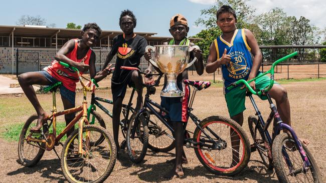 Tiwi locals on their bicycles posing for a picture with the women's trophy. Picture: Jono Laird.