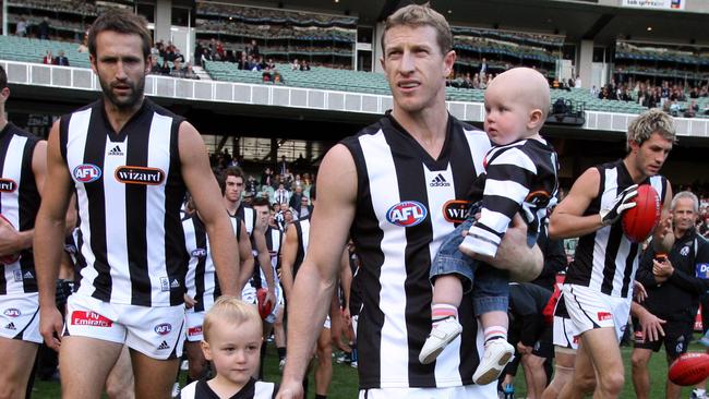 Former Collingwood captain Scott Burns walks out with his kids for his 250th game.