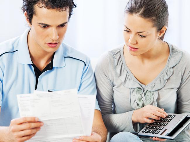 Young couple calculating their monthly finances at home. They are overwhelmed with bills.