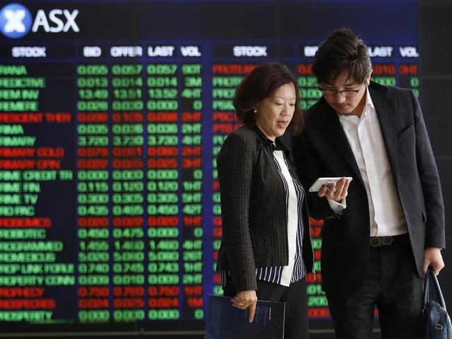 People look at a smartphone in front of electronic boards displaying stock information inside the Australian Securities Exchange, operated by ASX Ltd., in Sydney, Australia, on Thursday, Nov. 10, 2016. Stocks in Asia rebounded from their steepest slide since Brexit, industrial metals surged and regional bonds tumbled after Donald Trump's election victory and spending pledges spurred gains in U.S. shares. Photographer: David Moir/Bloomberg