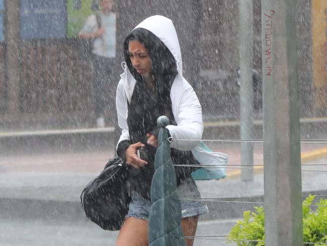 A young woman makes a run for it in the rain at Surfers Paradise this morning. Picture Glenn Hampson