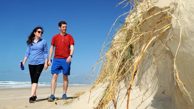 Becky and Daniel Corr from England walk past beach erosion during the windy weather. Picture: John Gass