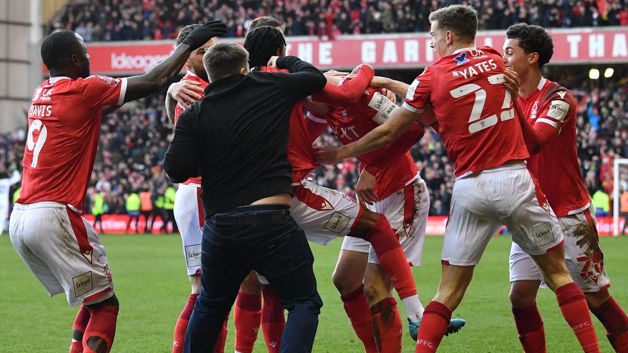 A supporter is tackled by stewards as Nottingham Forest's English defender Joe Worrall celebrates with his teammates after scoring their third goal during the English FA Cup fourth round football match between Nottingham Forest and Leicester City at The City Ground in Nottingham, central England, on February 6, 2022. (Photo by JUSTIN TALLIS / AFP) / RESTRICTED TO EDITORIAL USE. No use with unauthorised audio, video, data, fixture lists, club/league logos or 'live' services. Online in-match use limited to 120 images. An additional 40 images may be used in extra time. No video emulation. Social media in-match use limited to 120 images. An additional 40 images may be used in extra time. No use in betting publications, games or single club/league/player publications. /