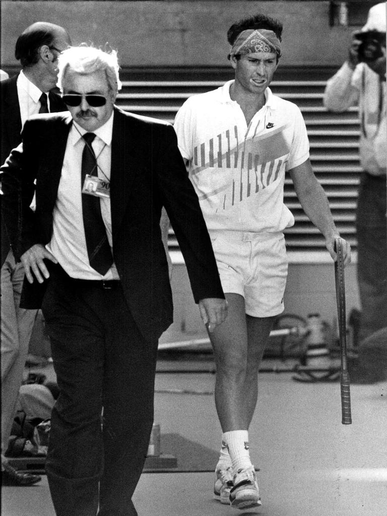 John McEnroe is escorted off Centre Court during the Australian Open in 1990 after he was defaulted for abusing an official during his fourth-round match. Picture: Photo File