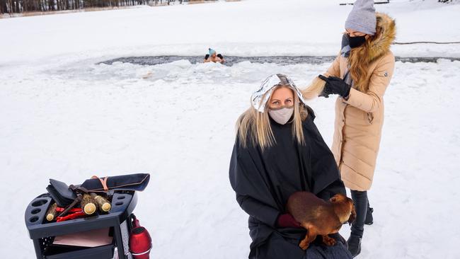 A hairdresser cuts hair on the frozen lake Babelitis while an ice swimmer takes a dip on in Riga, Latvia, as hairdressers are not allowed to work due to the pandemic. Picture AFP.