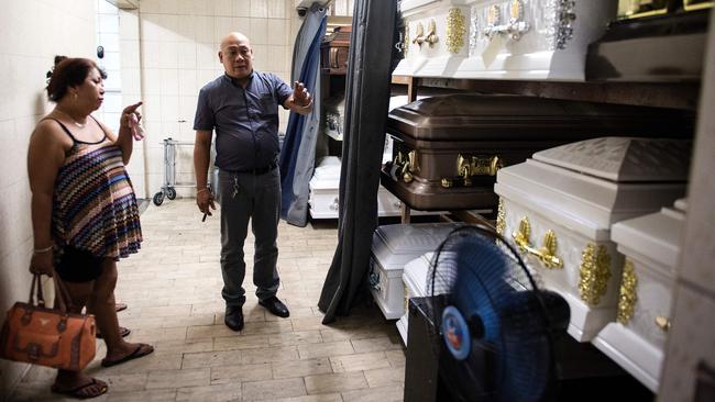 Veronica Memorial Chapel Funeral director Rico Teodocio talking to a relative of an alleged drug dealer who was killed by unidentified men about the prices of various coffins in Manila. Picture: AFP / Noel Celis.