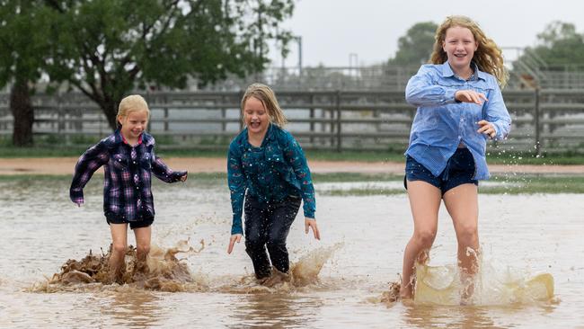 Estelle, Matilda and Edith Pearce playing in puddles in Barcaldine on Tuesday. Picture: Aaron Skinn