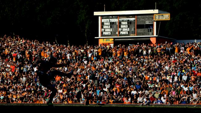 Players silhouetted with backdrop of crowd on hill as Brett Hodgson kicks for goal during Wests Tigers v Gold Coast Titans NRL game at Leichhardt Oval in Sydney.