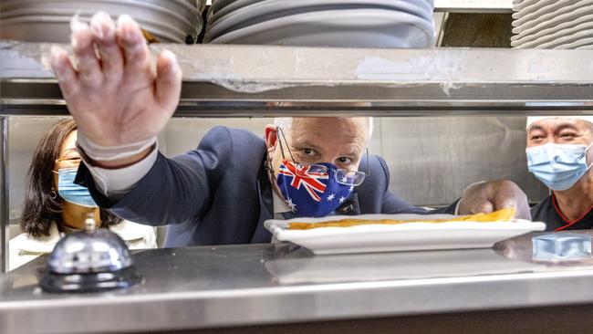 Scott Morrison rings the bell after making spring rolls at a Chinese restaurant in Box Hill. Picture: NCA NewsWire / David Geraghty