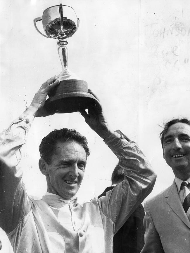 Jimmy Johnson holds aloft the Melbourne Cup after winning his third on Rain Lover in 1969.