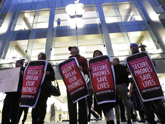 FILE - In this Tuesday, Feb. 23, 2016, file photo, protesters carry placards outside an Apple store in Boston. Tech companies, security experts and civil liberties groups are filing court briefs supporting Apple in its battle with the FBI. The groups oppose a judge’s order that would require Apple to help federal agents hack an encrypted iPhone used by a San Bernardino mass shooter. (AP Photo/Steven Senne, File)