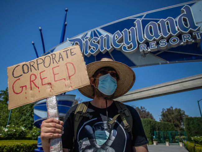 A man holds a sign in front of Disneyland Resort calling for higher safety standards before its reopening on July 17.