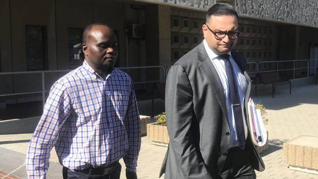 John Mugambi Mwamba walks out of Townsville Courthouse with his lawyer in 2021. Photo: Jacob Miley