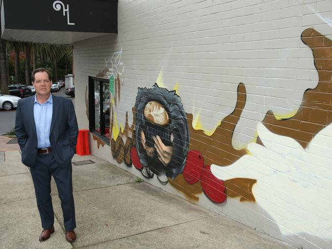 Cr Simon Menzies in front of the mural when it was incomplete.