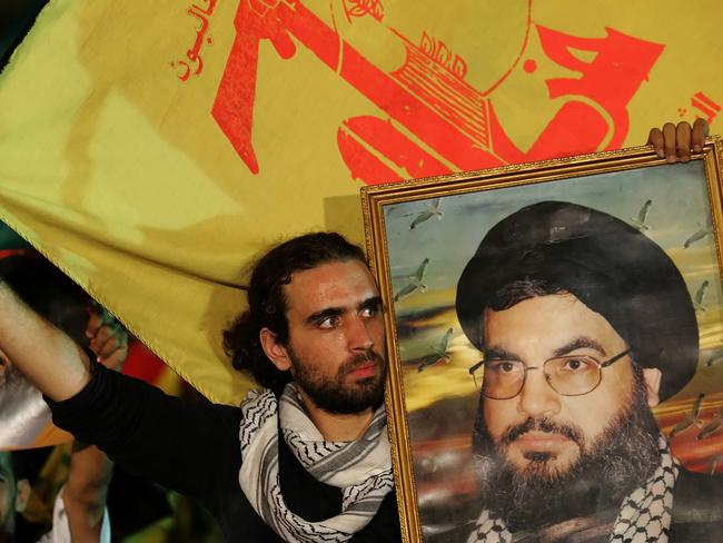 Lebanese Shiite men wave Hezbollah flags and hold up portraits of the group's leader Hassan Nasrallah. Picture: AFP