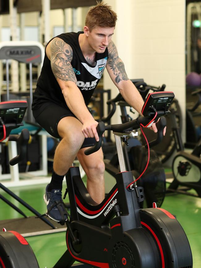 Port Adelaide’s Hamish Hartlett riding the stationary bike as he rehabilitates from a right knee reconstruction. Picture: Dylan Coker