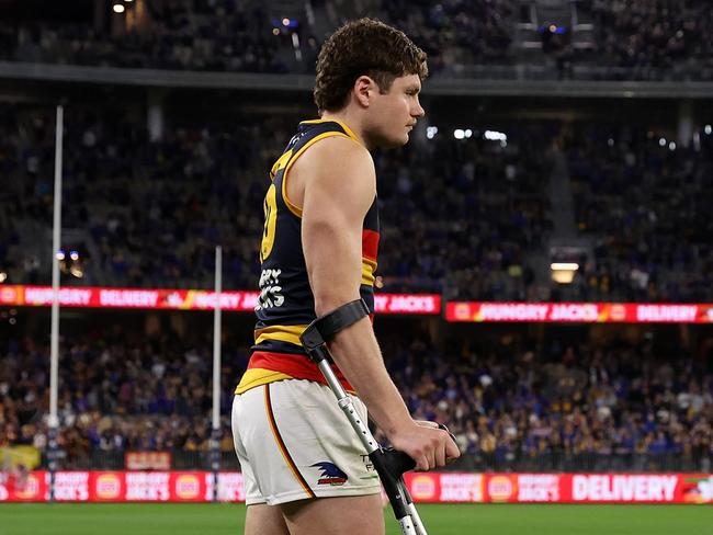 PERTH, AUSTRALIA - AUGUST 26: Harry Schoenberg of the Crows walks onto the field with the aid of crutches after the teams win during the 2023 AFL Round 24 match between the West Coast Eagles and the Adelaide Crows at Optus Stadium on August 26, 2023 in Perth, Australia. (Photo by Will Russell/AFL Photos via Getty Images)