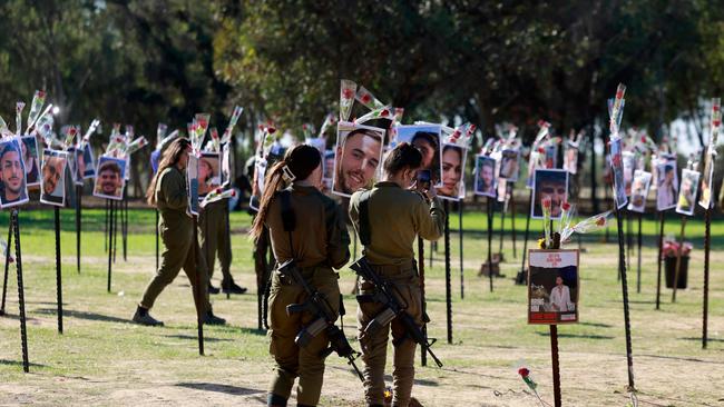 Israeli soldiers pay their respects at an installation bearing the photos of revellers who were killed or kidnapped during the October 7 attack at the site of the Nova festival in Re'im. Picture: AFP