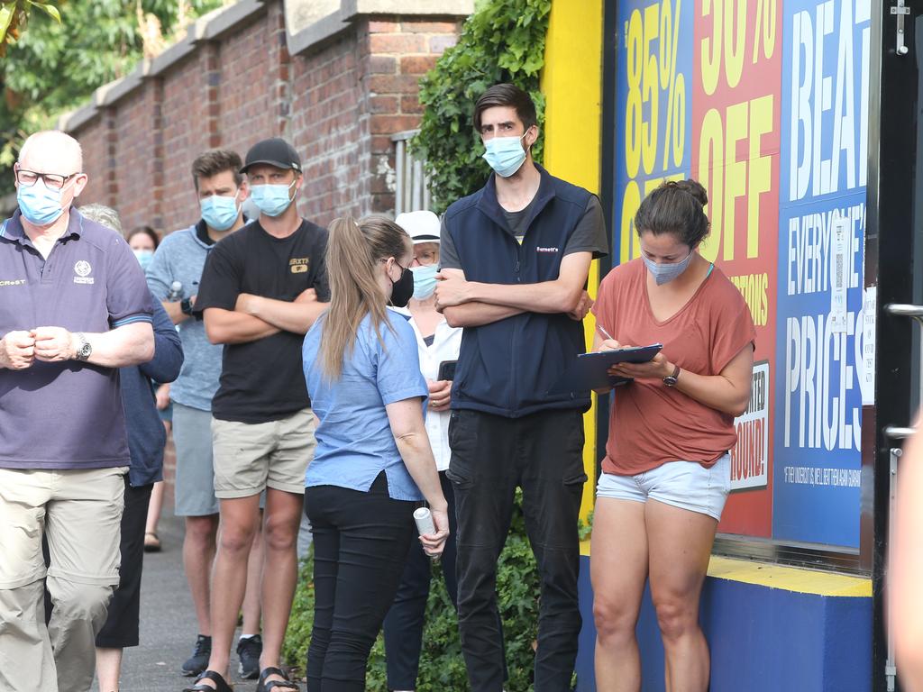 Staff taking details to inform customers of RAT stock availability in a queue outside a Chemist Warehouse store in Melbourne. Picture: Alan Barber