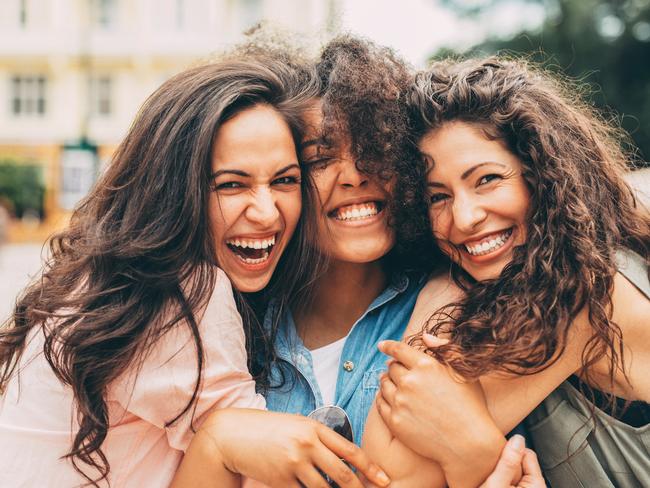 Three best friends hugging each other in the city.