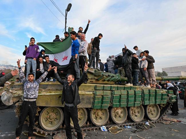 TOPSHOT - People celebrate with anti-government fighters at Umayyad Square in Damascus on December 8, 2024. Islamist-led rebels declared that they have taken Damascus in a lightning offensive on December 8, sending President Bashar al-Assad fleeing and ending five decades of Baath rule in Syria. (Photo by LOUAI BESHARA / AFP)