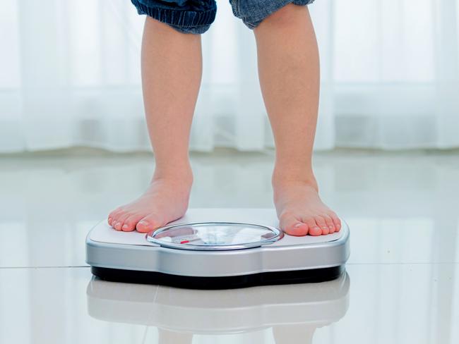 Boy measures weight on a weight scale.