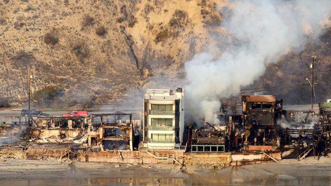 TOPSHOT - In this aerial view taken from a helicopter, burned homes are seen from above during the Palisades fire in Malibu, Los Angeles county, California on January 9, 2025. Massive wildfires that engulfed whole neighborhoods and displaced thousands in Los Angeles remained totally uncontained January 9, 2025, authorities said, as US National Guard soldiers readied to hit the streets to help quell disorder. Swaths of the United States' second-largest city lay in ruins, with smoke blanketing the sky and an acrid smell pervading almost every building. (Photo by JOSH EDELSON / AFP)