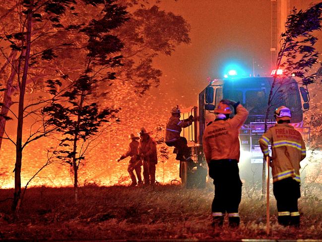 Firefighters hose down trees as they battle against bushfires around the town of Nowra in the Australian state of New South Wales on December 31, 2019. - Thousands of holidaymakers and locals were forced to flee to beaches in fire-ravaged southeast Australia on December 31, as blazes ripped through popular tourist areas leaving no escape by land. (Photo by SAEED KHAN / AFP)