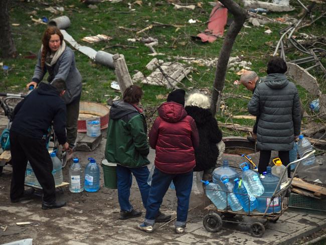 People carry mineral water in Mariupol as Russian troops intensify a campaign to take the strategic port city. Picture: AFP