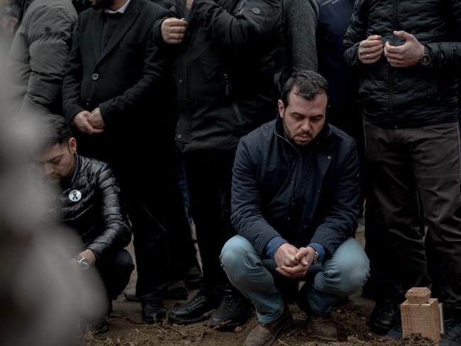 A family member reflects at a graveside as family and friends gather at the cemetary after the funeral of eight victims who died followingthe ski resort fire. Picture: AFP