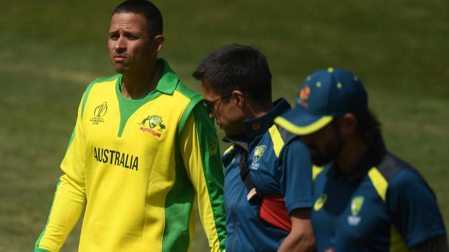 Usman Khawaja is escorted off the field after being struck in the jaw.